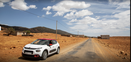 Une voiture louée de l'agence Tourvilles location voiture fes aeroport se frayant un chemin à travers les dunes dorées du désert, offrant une liberté totale pour explorer les vastes étendues sauvages et majestueuses de cette région fascinante.