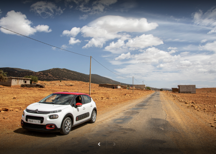 Une voiture louée de l'agence Tourvilles location voiture fes aeroport se frayant un chemin à travers les dunes dorées du désert, offrant une liberté totale pour explorer les vastes étendues sauvages et majestueuses de cette région fascinante.